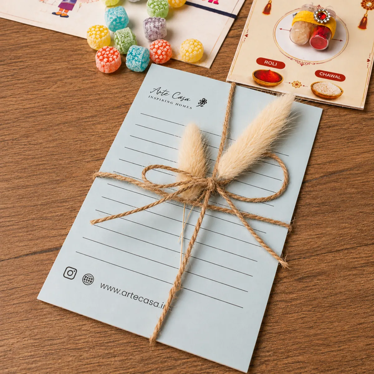 Blue handwritten note card tied with twine beside colourful festive hamper items