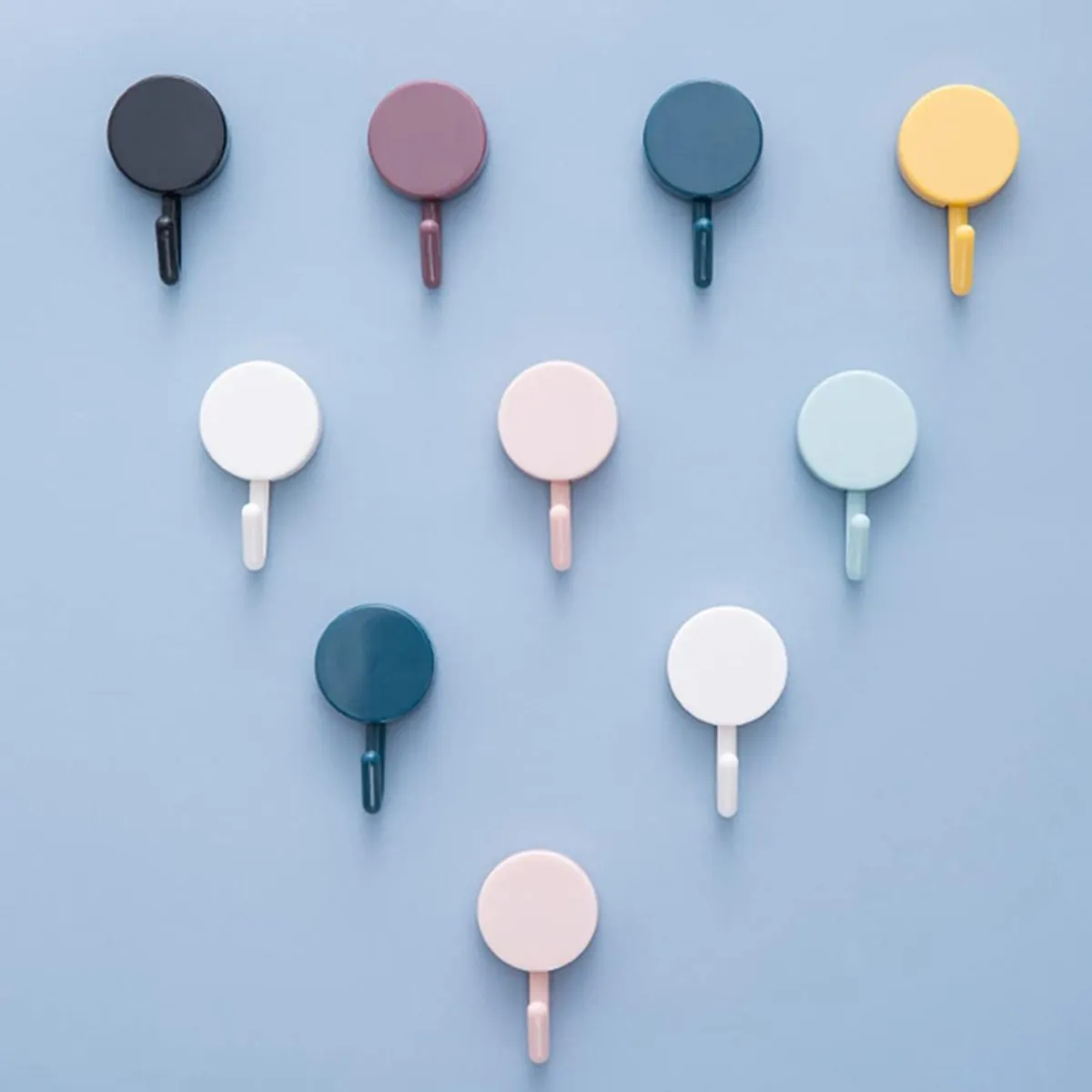 Ten multicolour round hooks arranged in rows on a pale blue wall.
