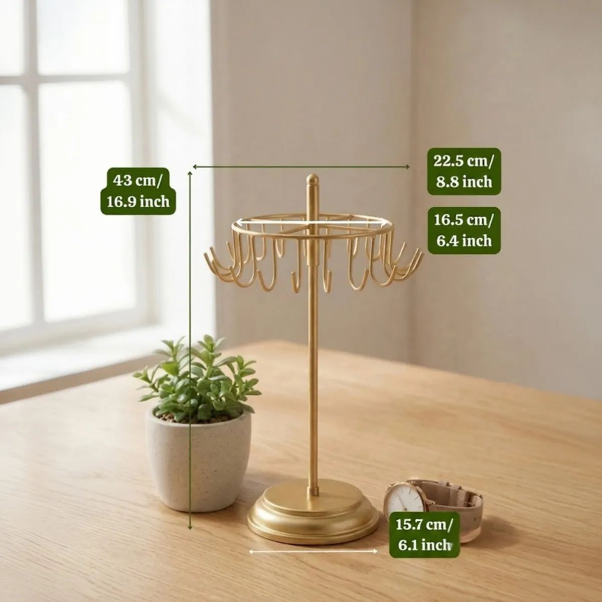 Gold jewellery stand on a wooden table beside a plant and watch.