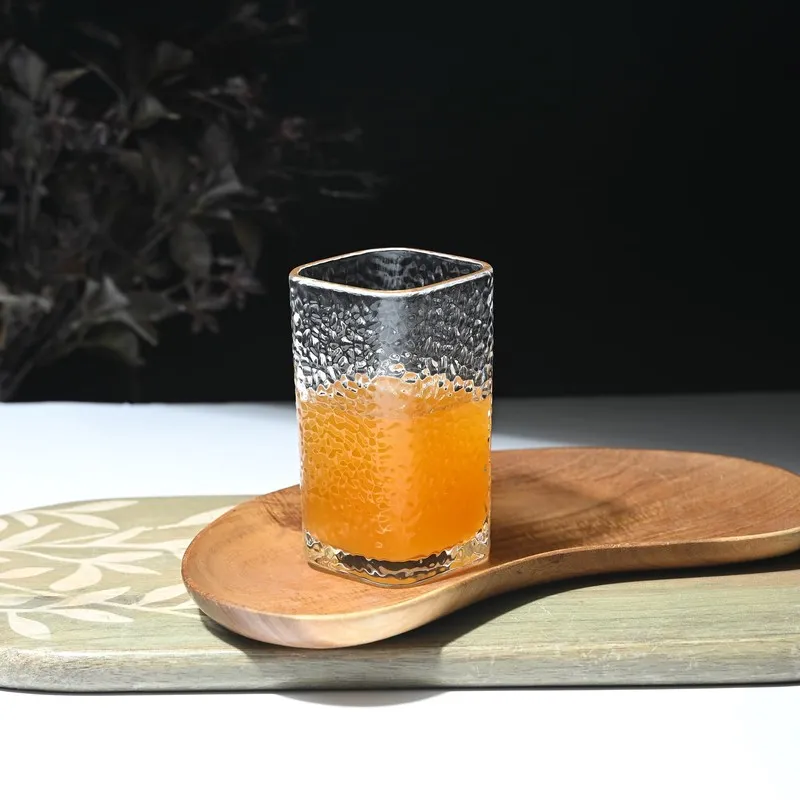 Single clear textured glass with orange juice on a wooden platter