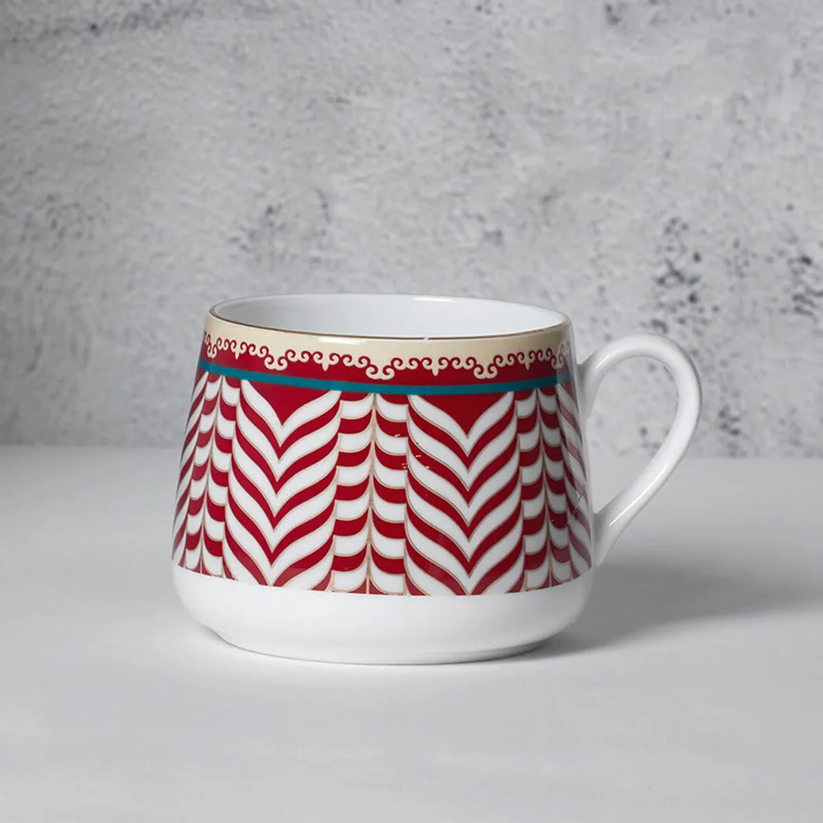 Close-up of a white cup with red chevron pattern and gold detailing