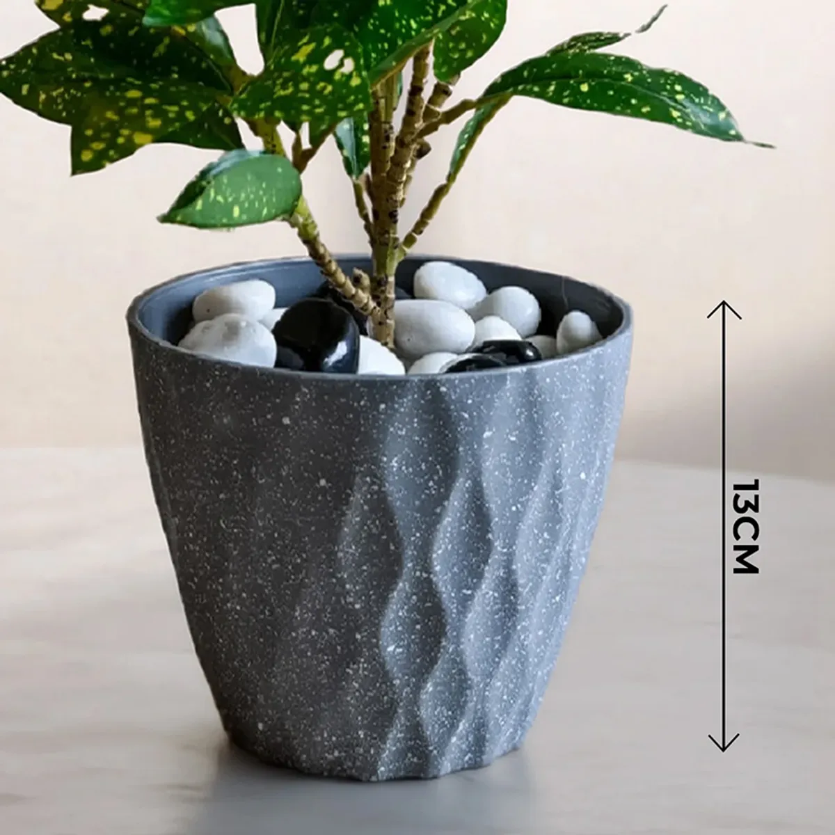 Close-up of a grey textured planter with speckled finish and decorative stones