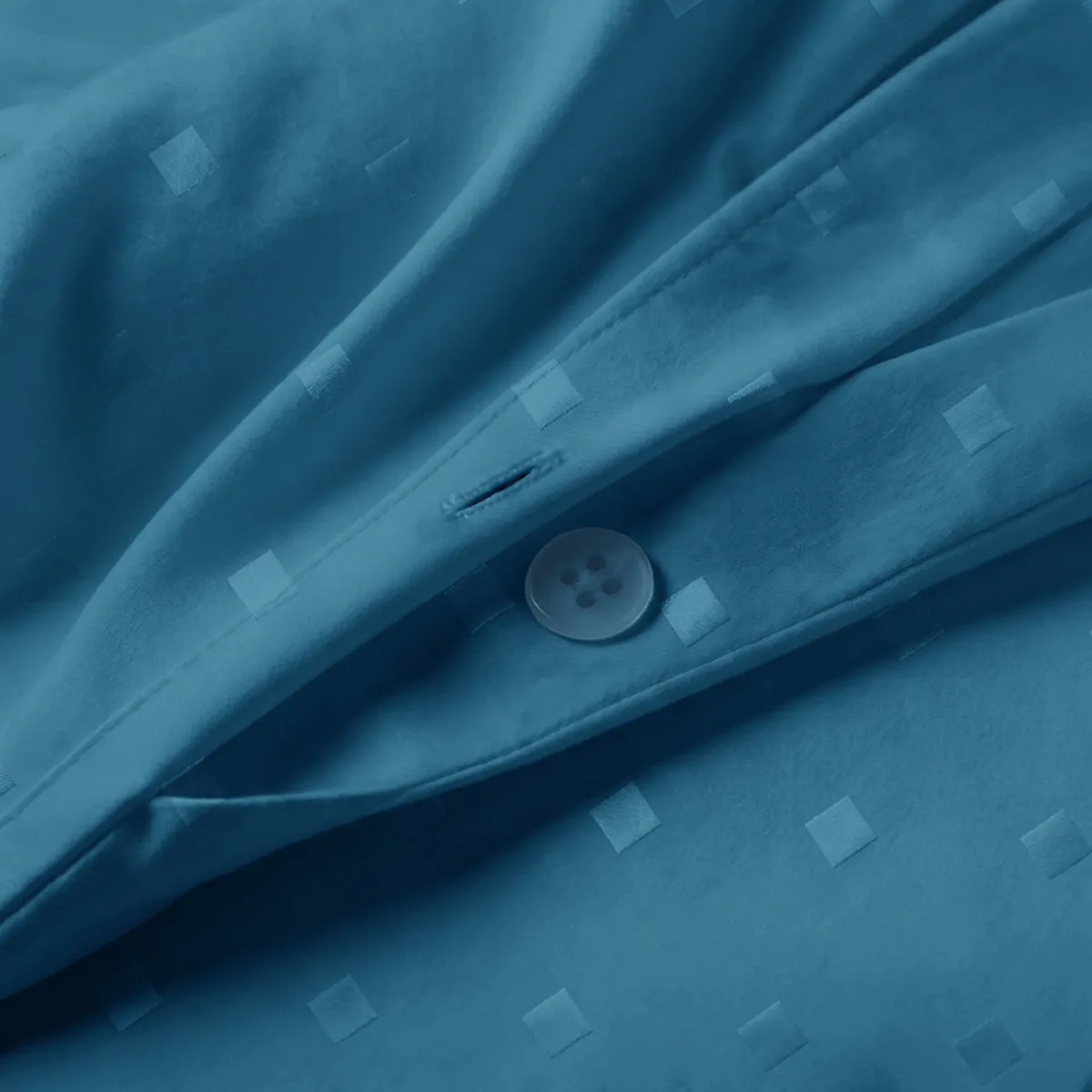 Close-up of azure blue cotton duvet cover showing square pattern and button closure