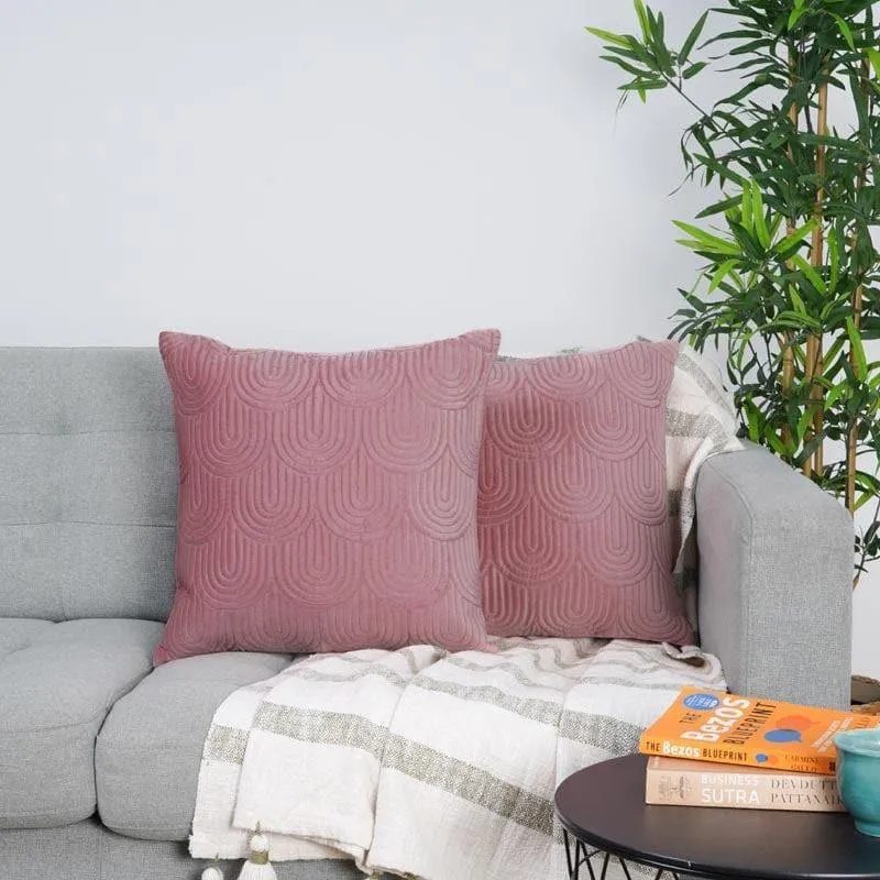 Two pink patterned cushion covers arranged on a grey sofa