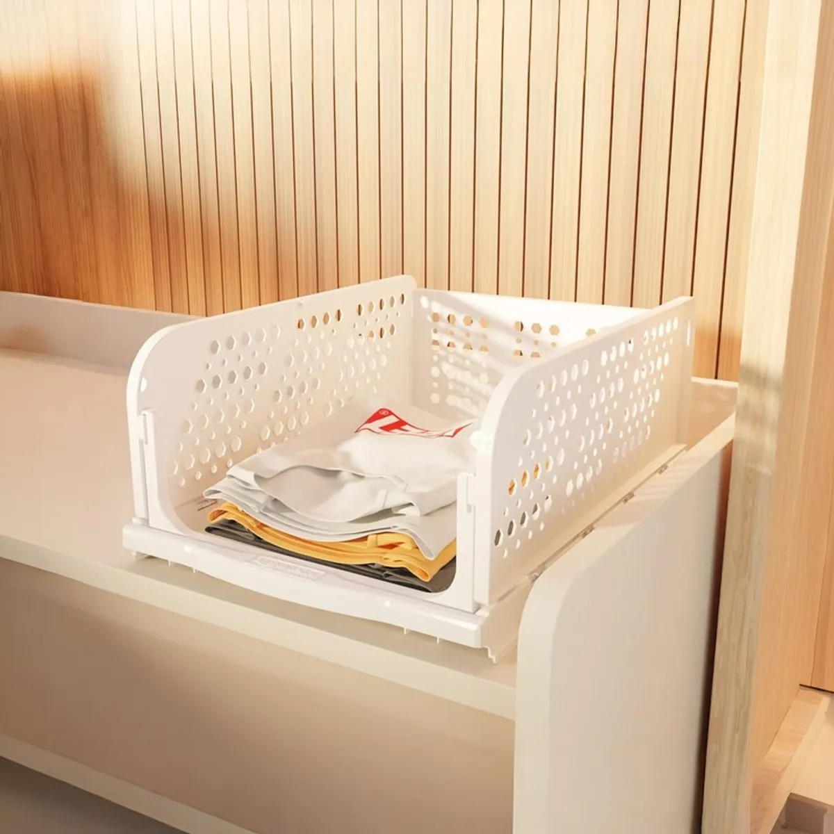 White perforated organiser holding folded clothing on a shelf