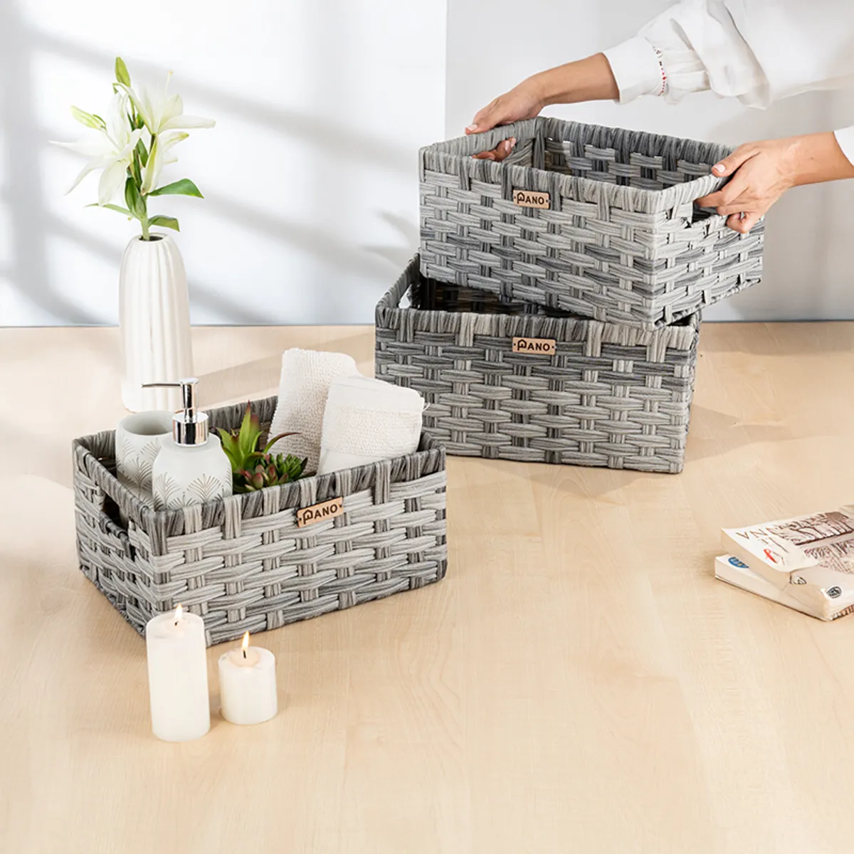 Three grey woven-look storage baskets on a table, one filled with toiletries and towels