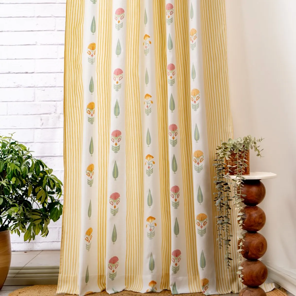 Full-length yellow curtains with floral and leafy motifs in a bright room