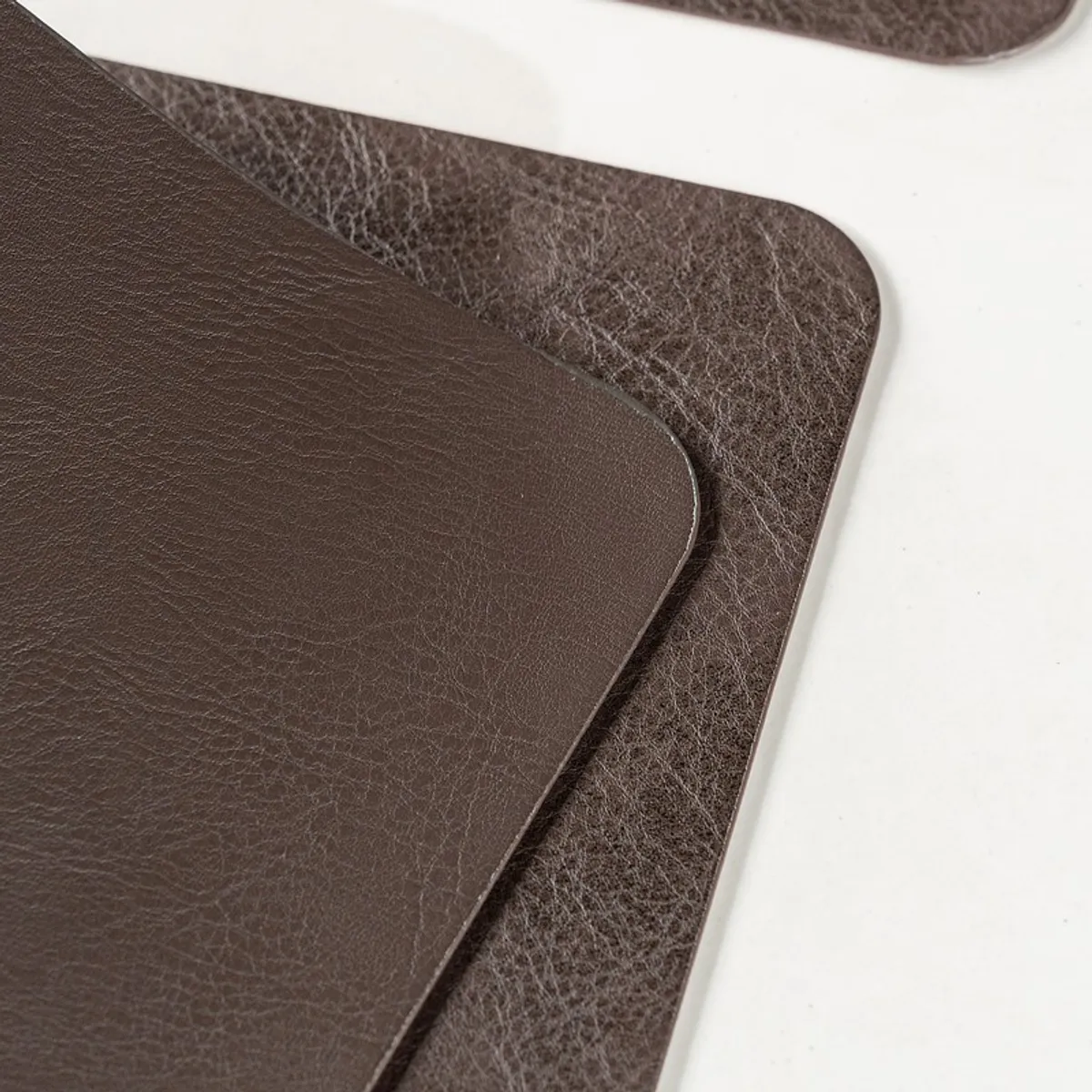 Close-up of stacked brown table mats with rounded corners and textured surface