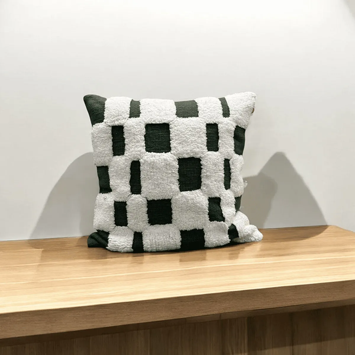 Square tufted checked cushion cover displayed on a wooden console
