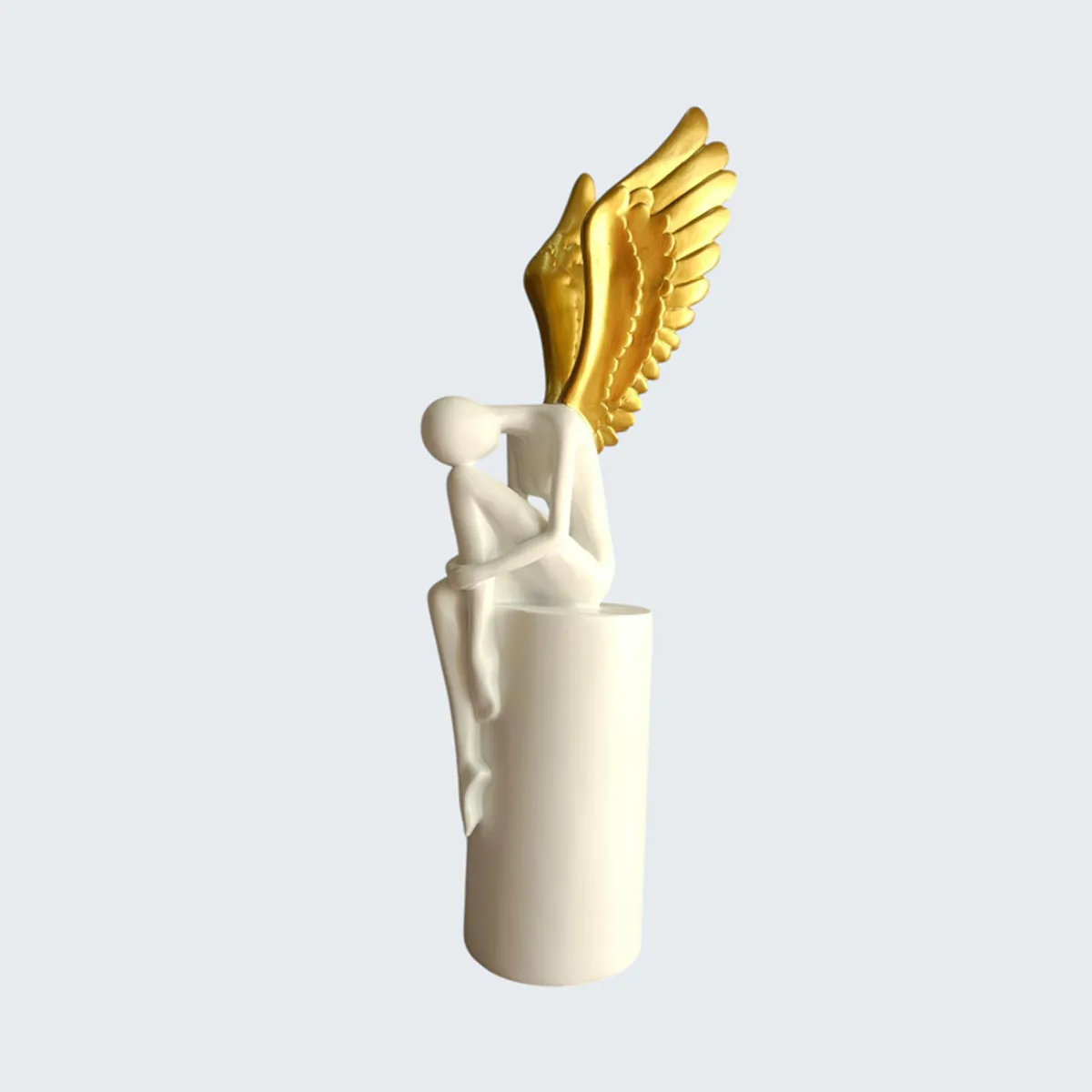Profile view of a white and gold seated winged abstract figurine