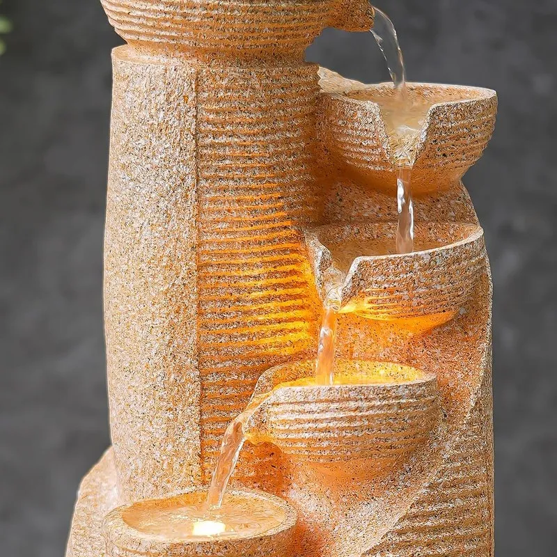 Close-up of tiered bowls and flowing water with warm LED lighting