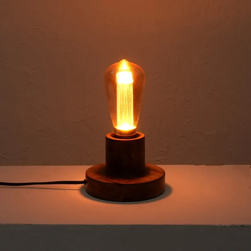 Lit brown table lamp with warm glowing glass bulb against a textured wall