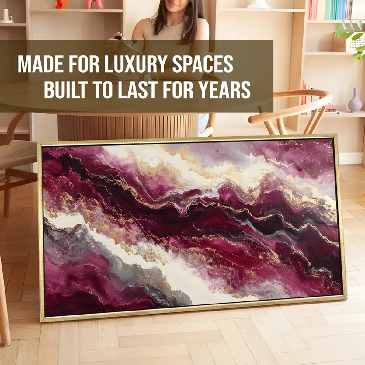 Framed abstract painting in plum, white and gold leaning in a room