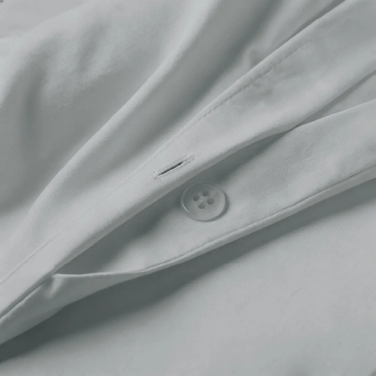Close-up of light grey duvet cover fabric and button fastening