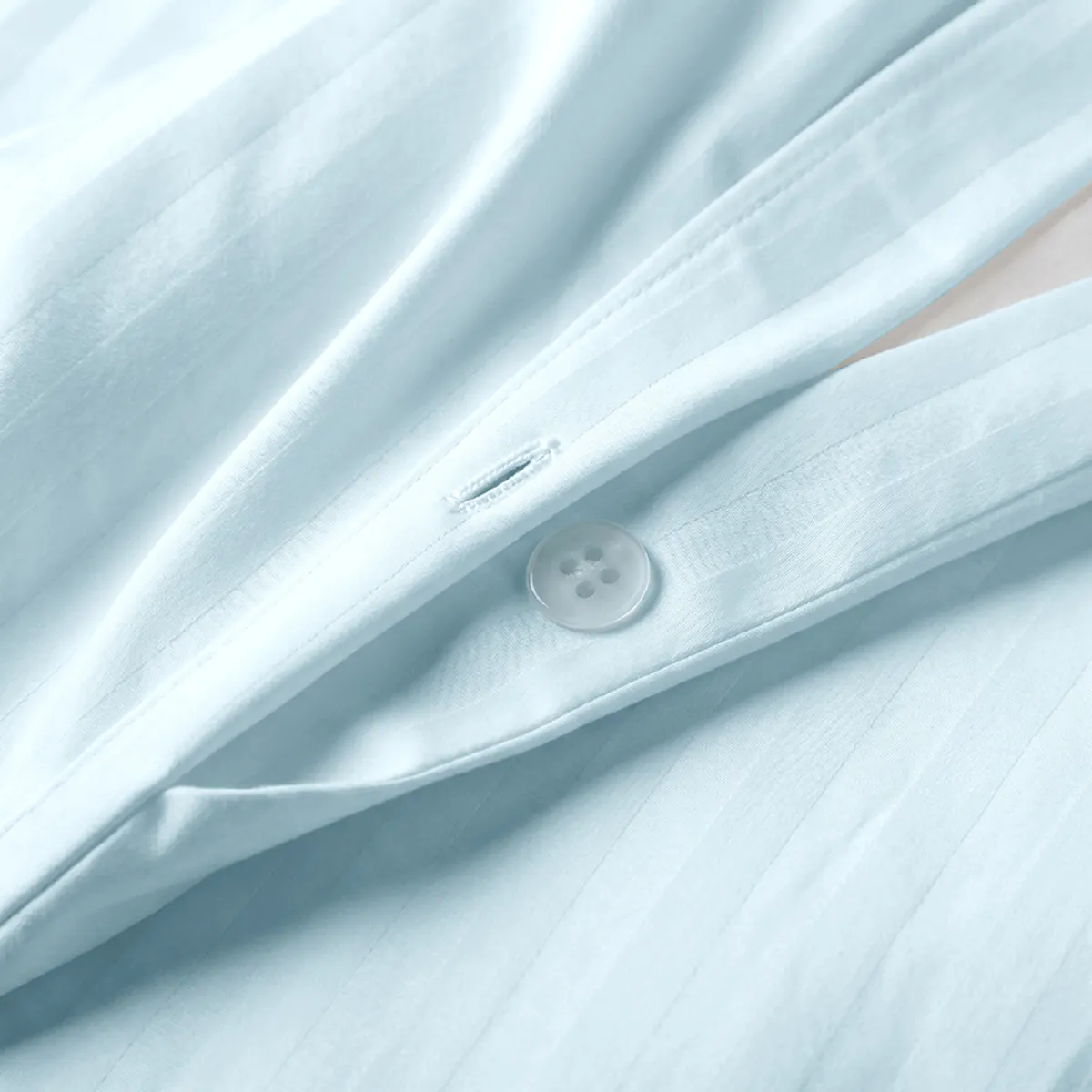 Close-up of pale blue cotton duvet cover fabric with button fastening