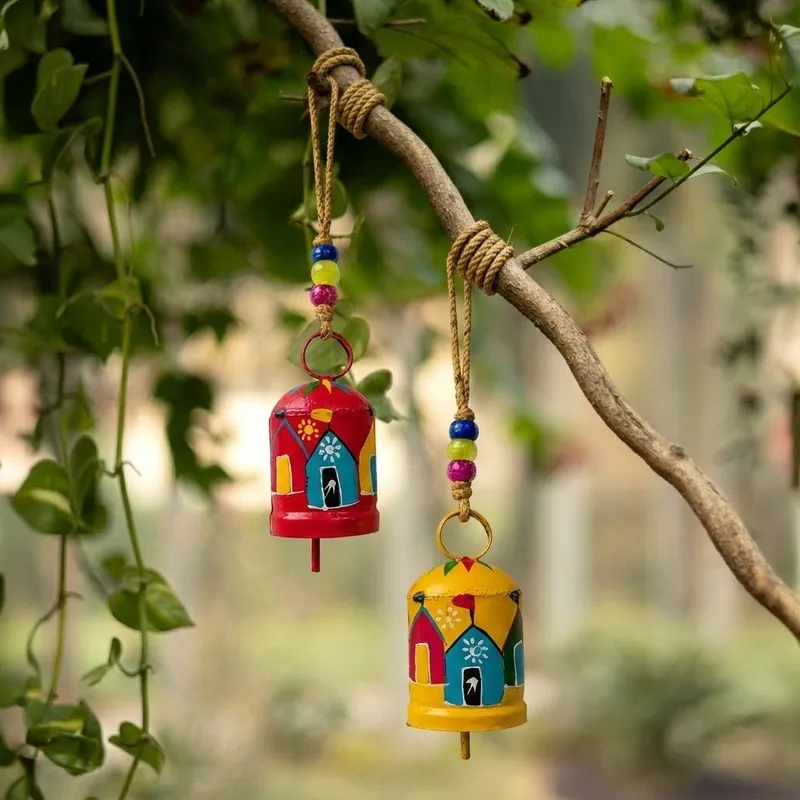 Two hand-painted hanging bells in red and yellow hanging from a branch