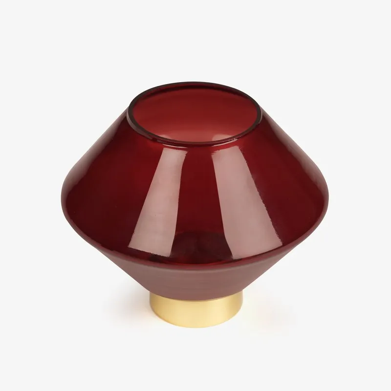 Ruby red glass candle holder with gold base on a white background