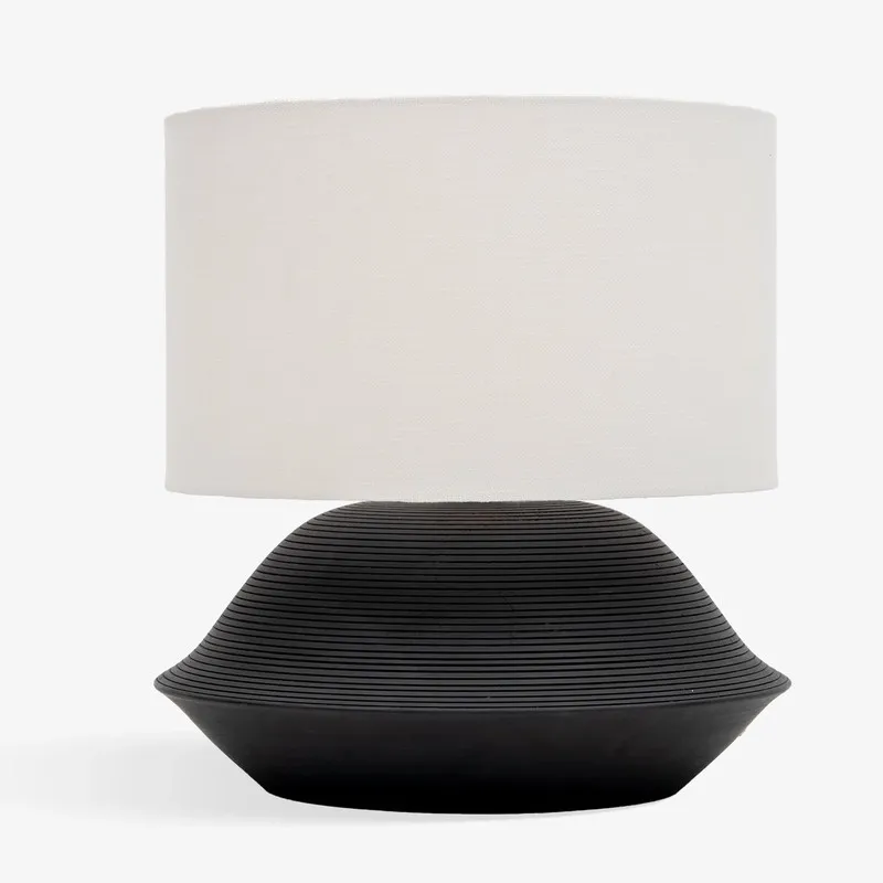Studio view of black table lamp with plain light shade on white background