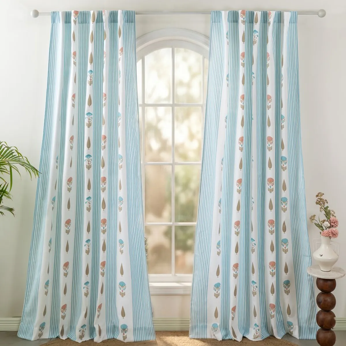 Pair of patterned blue and white curtains framing an arched window