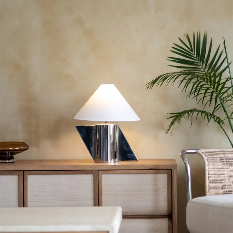 Modern white and silver table lamp on a console beside a chair