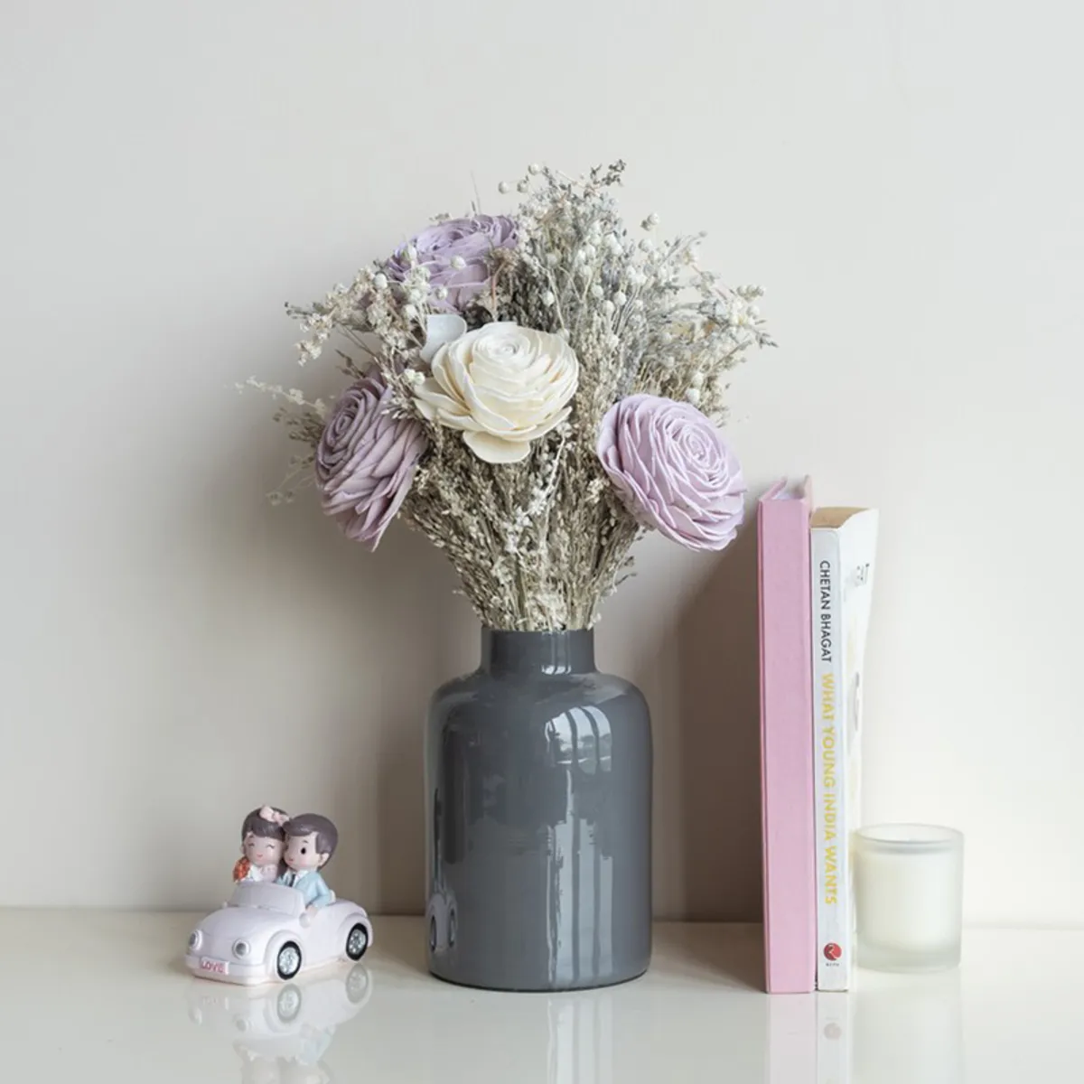 Wild Garden posy arranged in a dark vase beside books and a decorative figurine