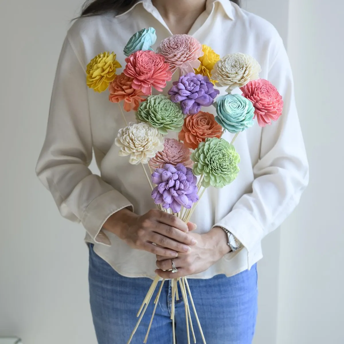 Person holding a vibrant multicolour bouquet of artificial flower sticks