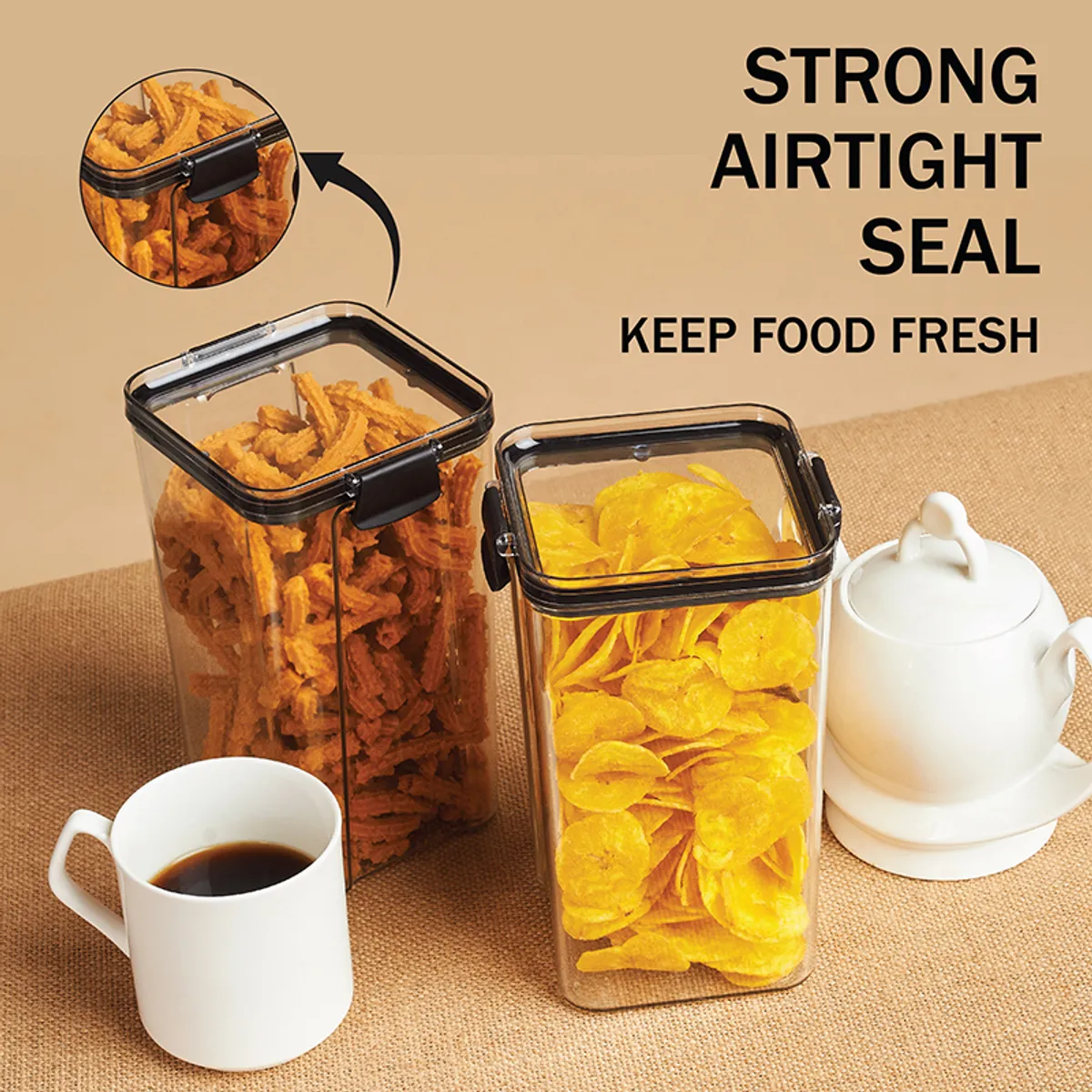 Two tall clear airtight containers with black lids beside cups and snacks
