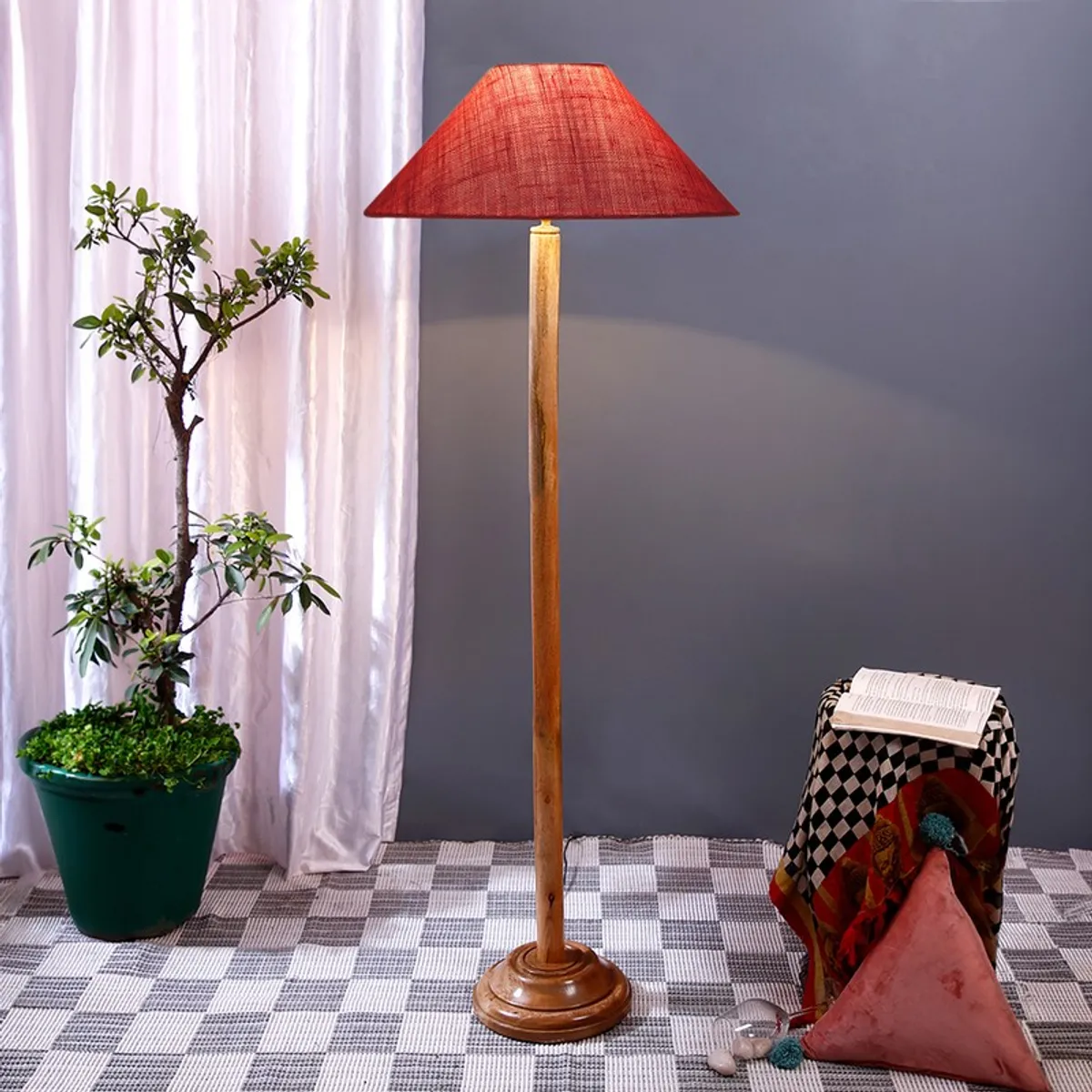 Wooden floor lamp with a pink textured shade in a styled room setting