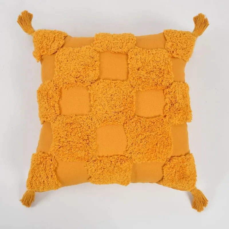 Front view of a yellow tufted cushion cover with checkerboard texture and corner tassels