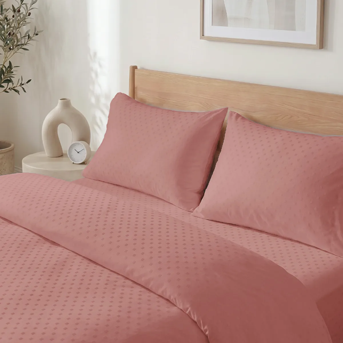 Angled view of rose-brown dotted duvet cover and pillows on a wooden bed