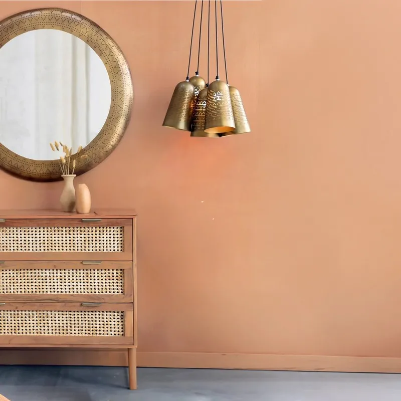 Gold bell cluster ceiling lamp suspended against a peach wall