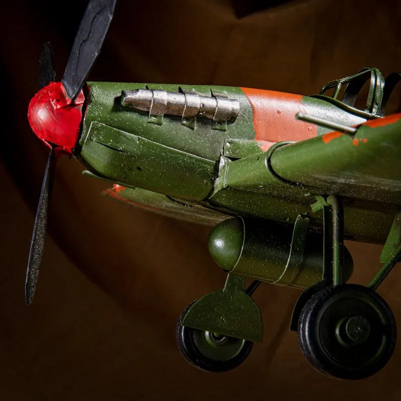 Side close-up of the green and red metal aeroplane showpiece with landing wheels