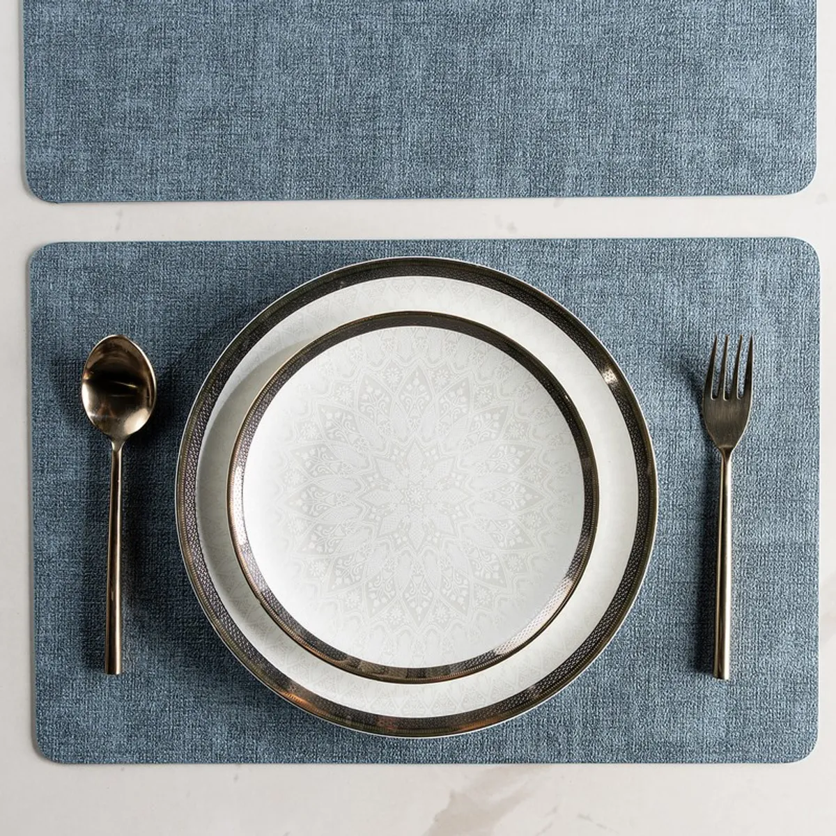 Top view of a blue rectangular table mat with plate and cutlery