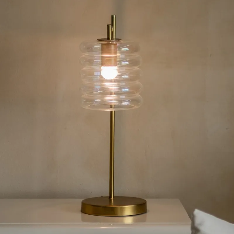 Close view of lit transparent ribbed glass shade on a gold-toned table lamp