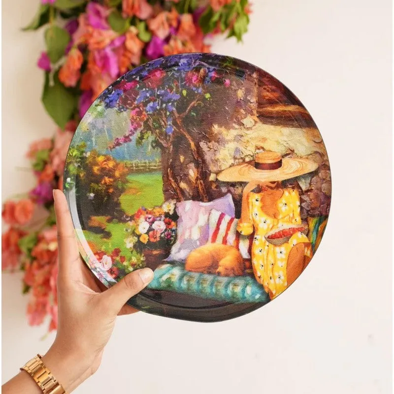 Close-up of a round wall plate showing a seated figure beneath a flowering tree.