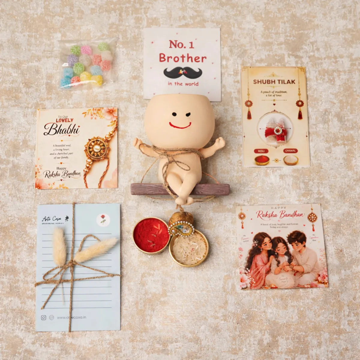 Rakhi hamper contents arranged around a smiling planter, cards, candies and ritual essentials