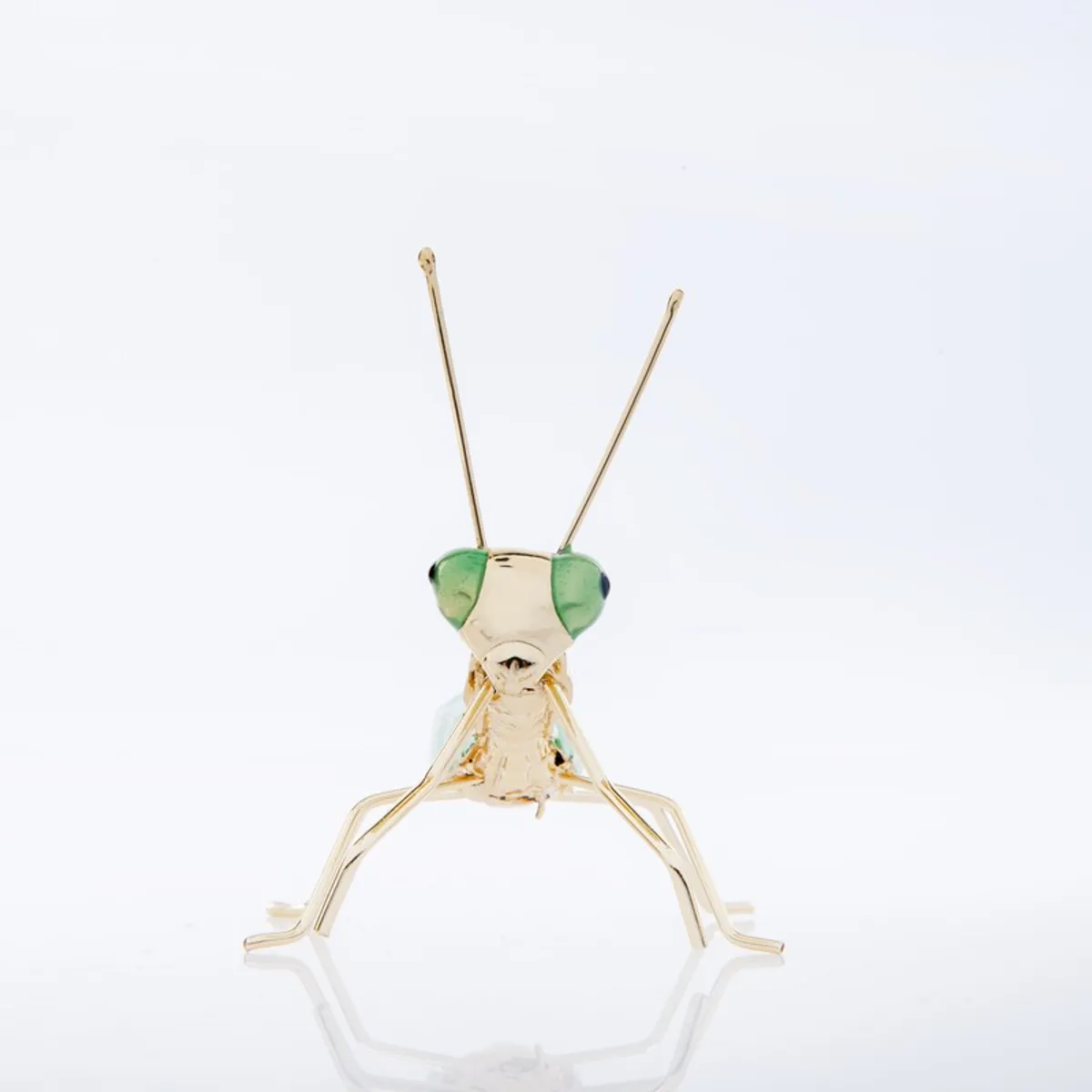 Front view of a green and gold praying mantis figurine