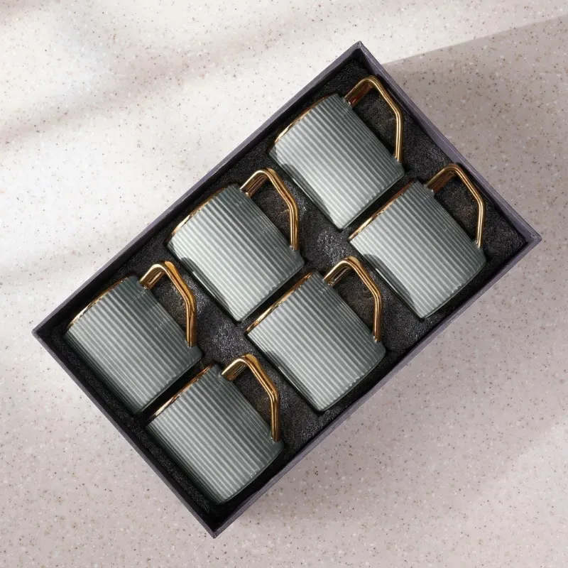 Top view of six grey ribbed mugs with gold-toned handles placed in a box