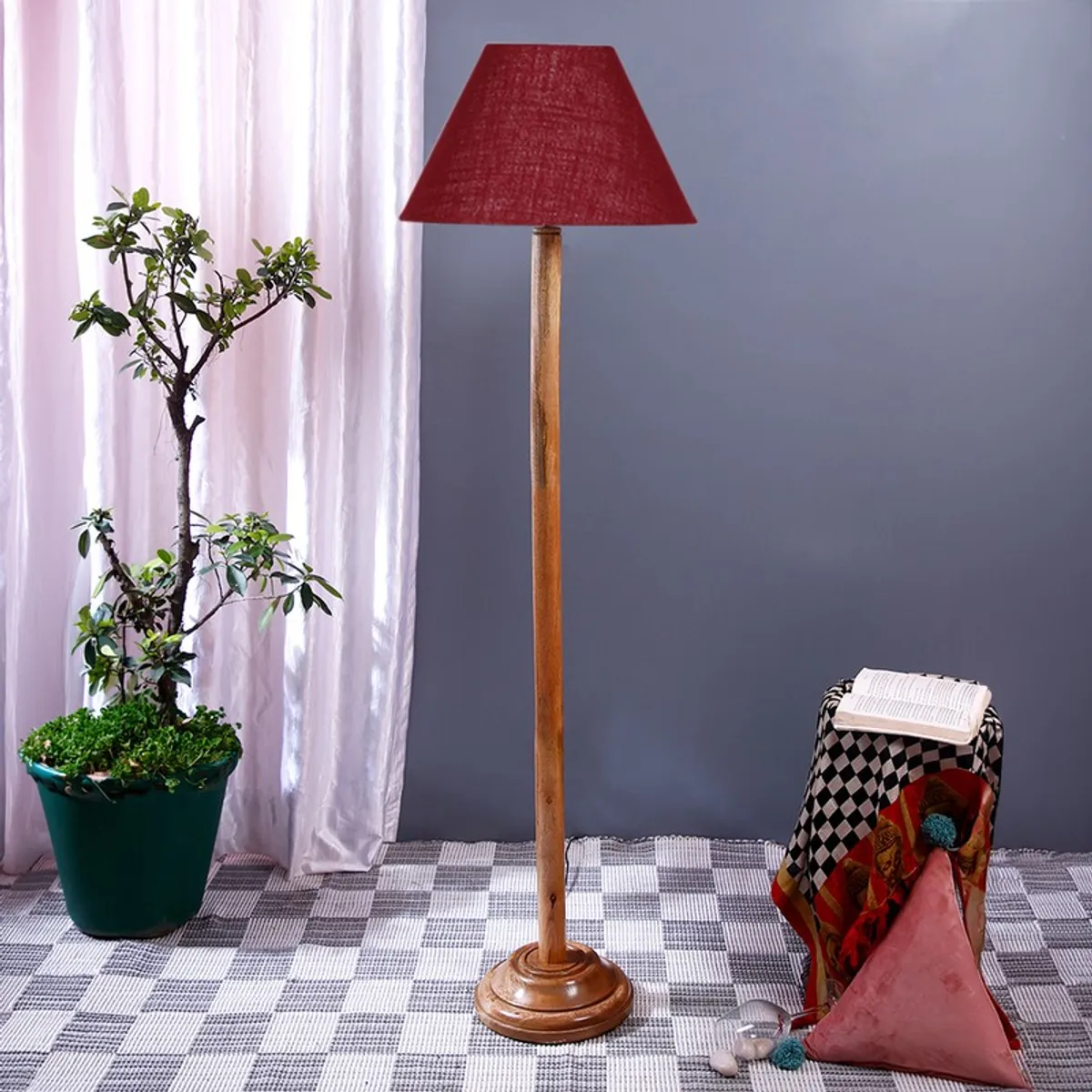 Wooden floor lamp with deep burgundy conical shade in an indoor setup