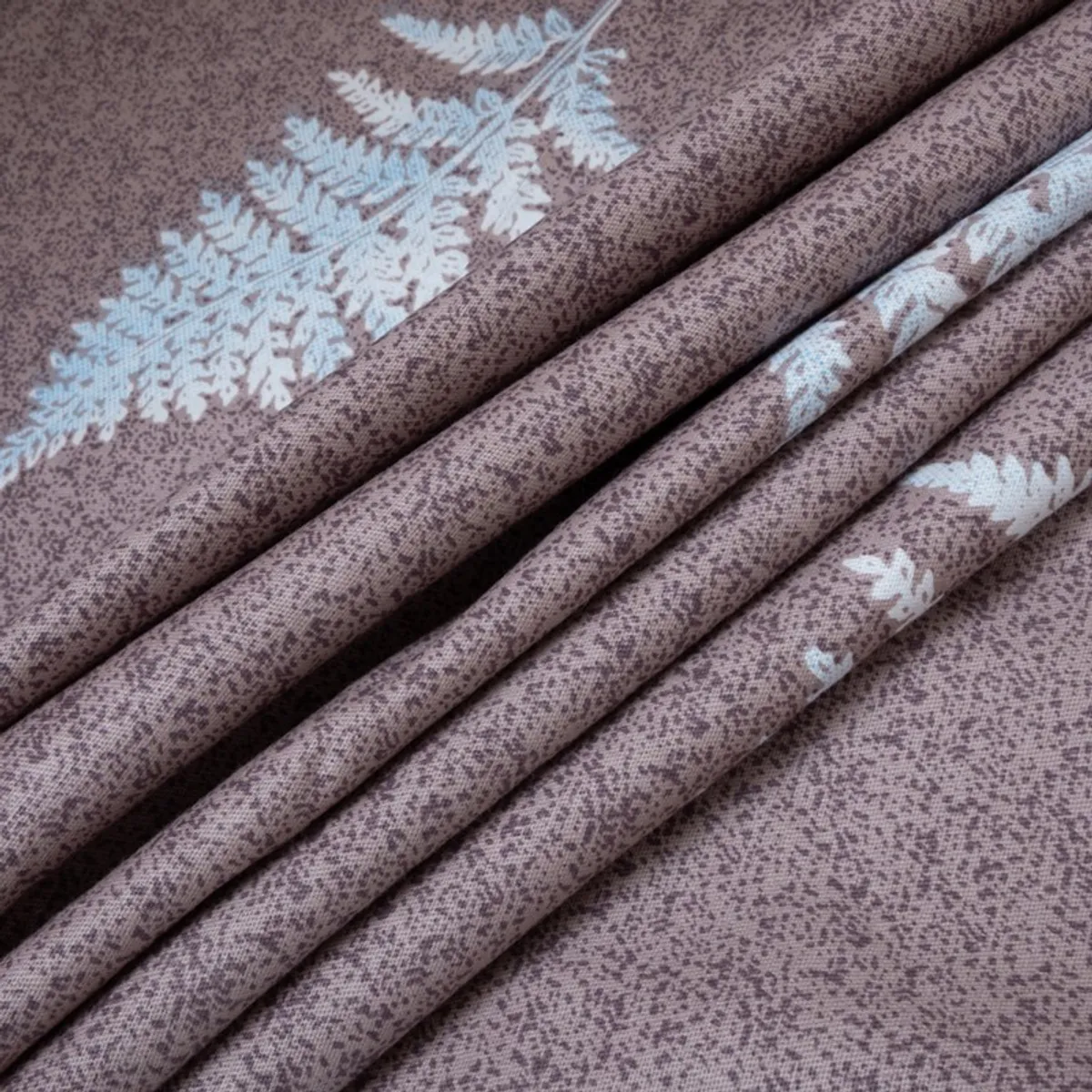 Folded purple printed fabric showing blue and white botanical motifs