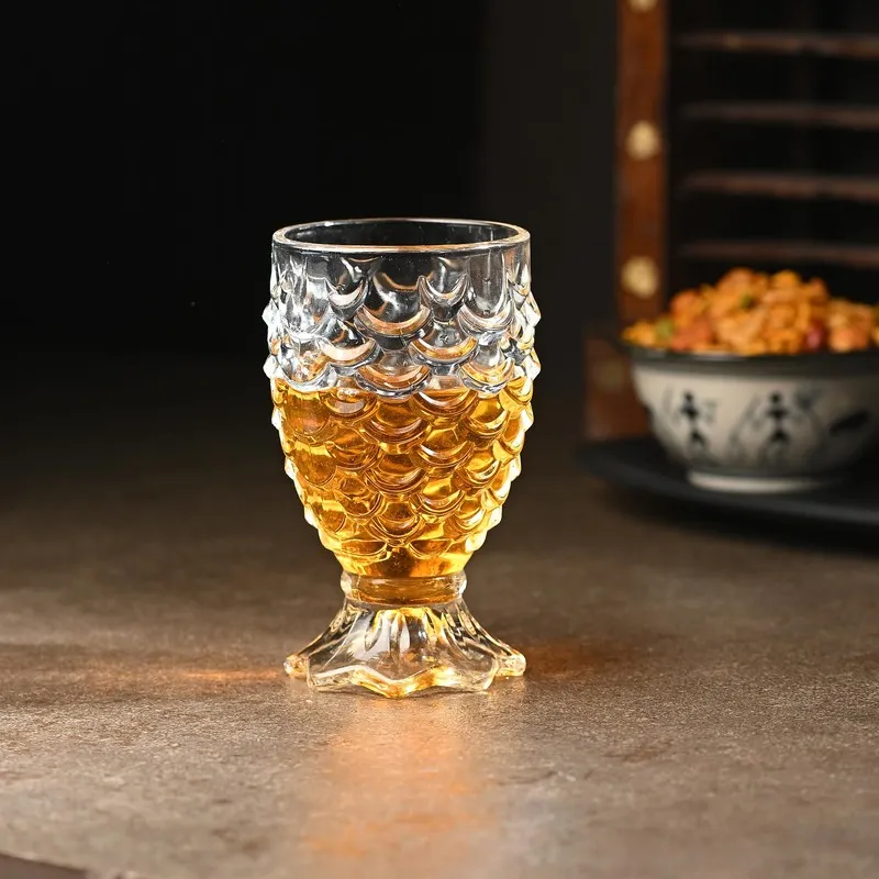 Clear cocktail glass filled with an amber drink, featuring a scalloped embossed body