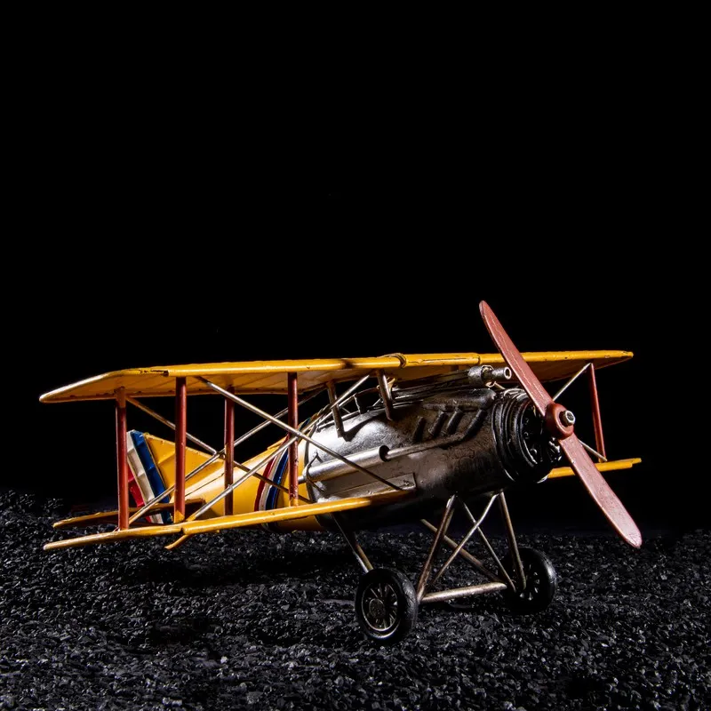 Side view of a yellow vintage biplane showpiece against a black background