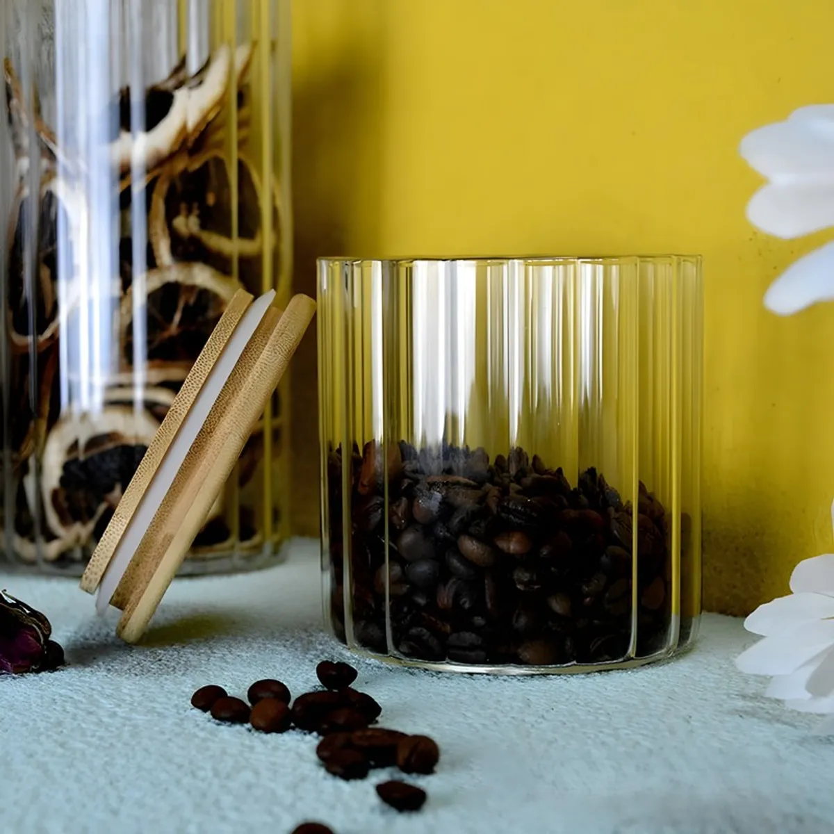 Open clear fluted glass jar with its bamboo lid leaning beside it.