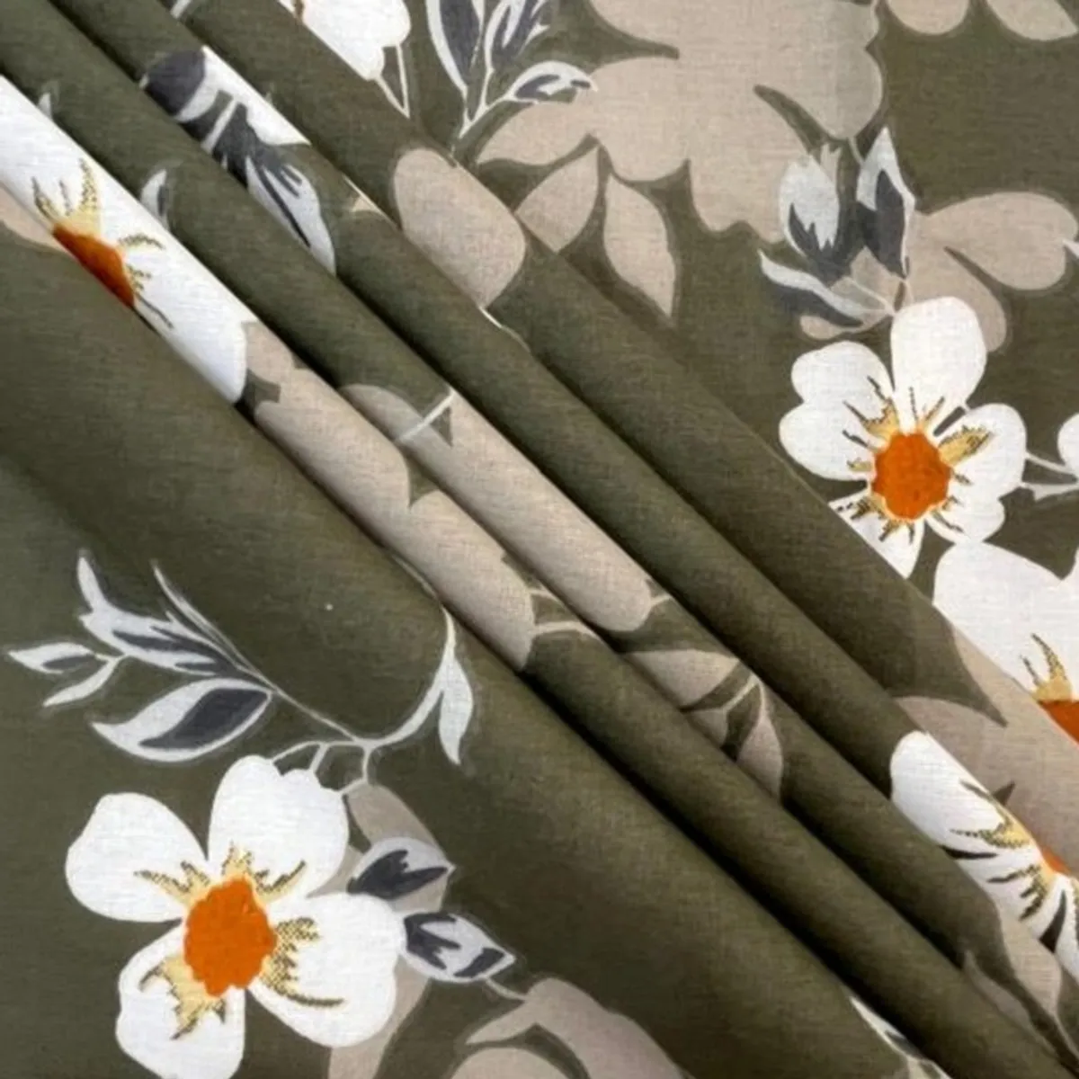 Close-up of green floral cotton fabric with white and orange flowers