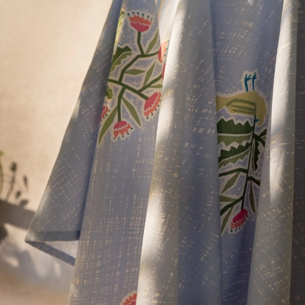 Close-up of floral motifs and textured light blue curtain folds