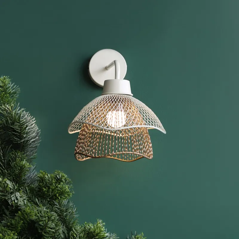 Close view of white wall lamp with layered gold-toned mesh shade