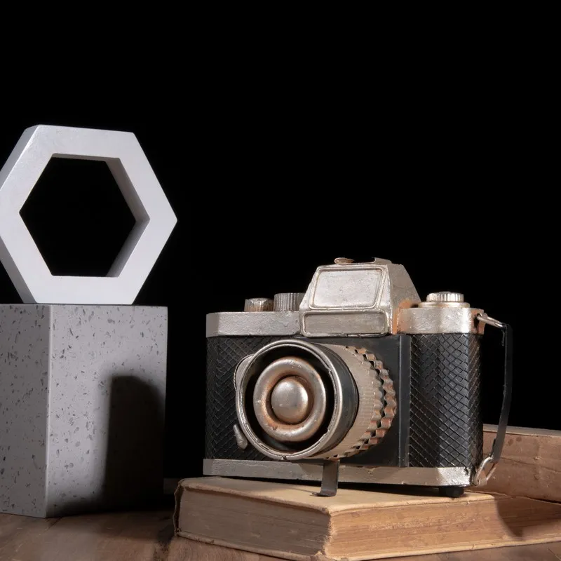 Black and silver camera showpiece styled on stacked books against a dark background