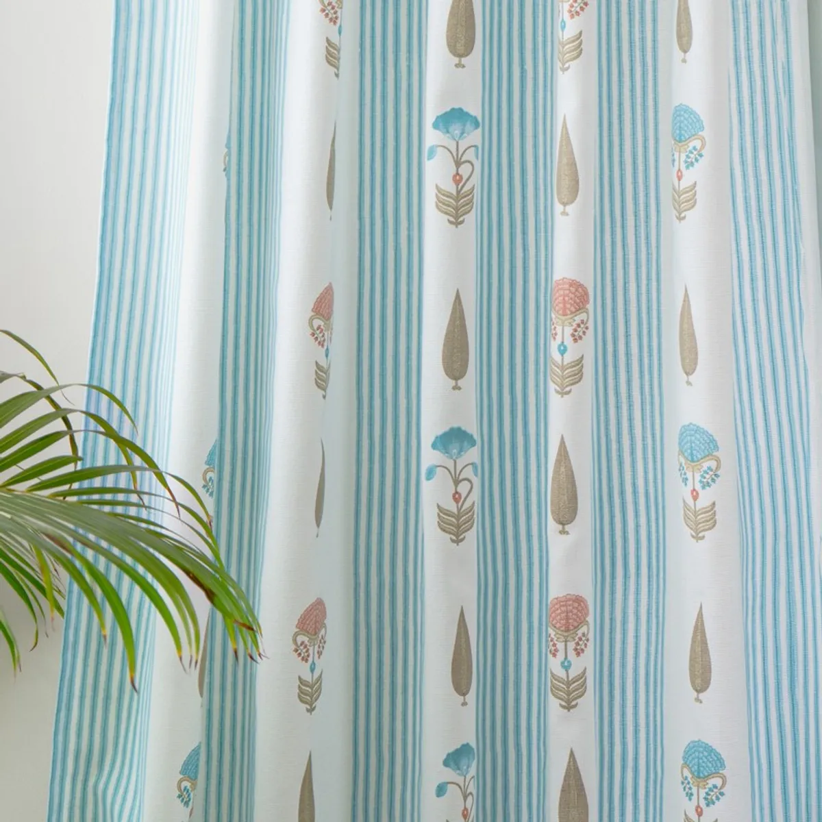 Close-up of white curtains with blue stripes and repeated floral motifs
