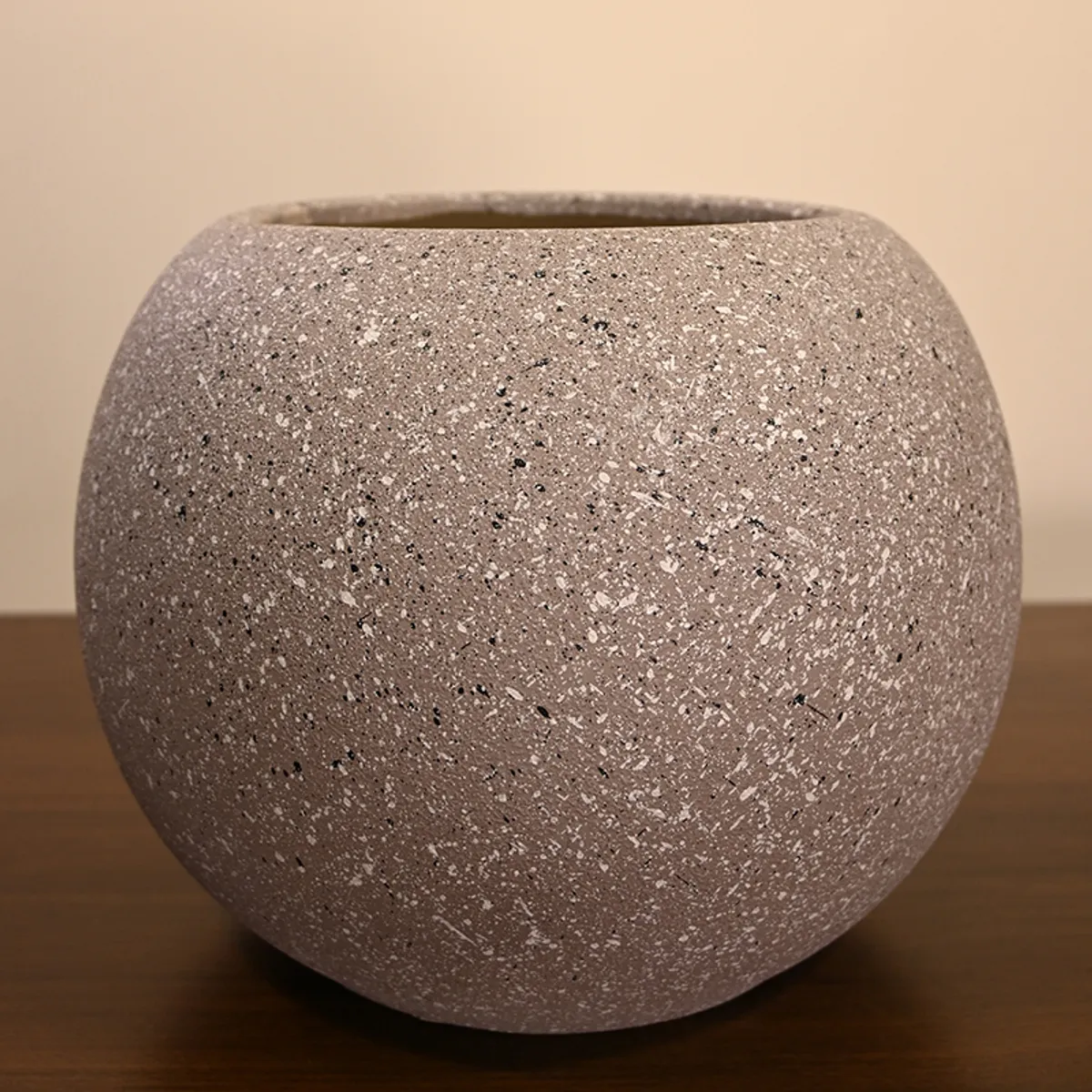 Close-up of a round grey-brown speckled planter with a matte surface