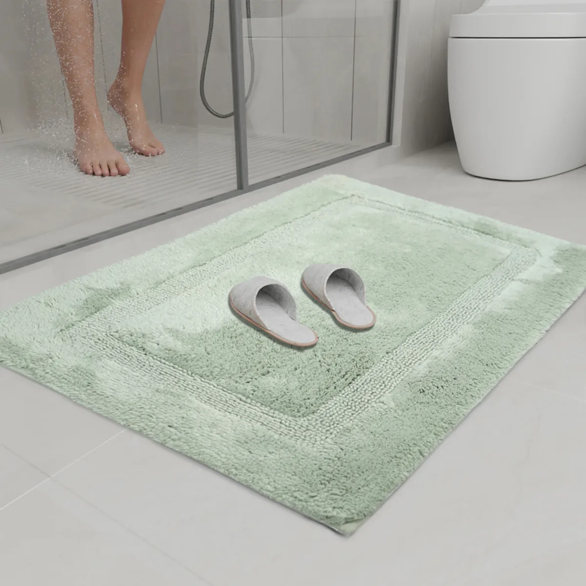 Green geometric bath mat positioned beside a glass shower enclosure